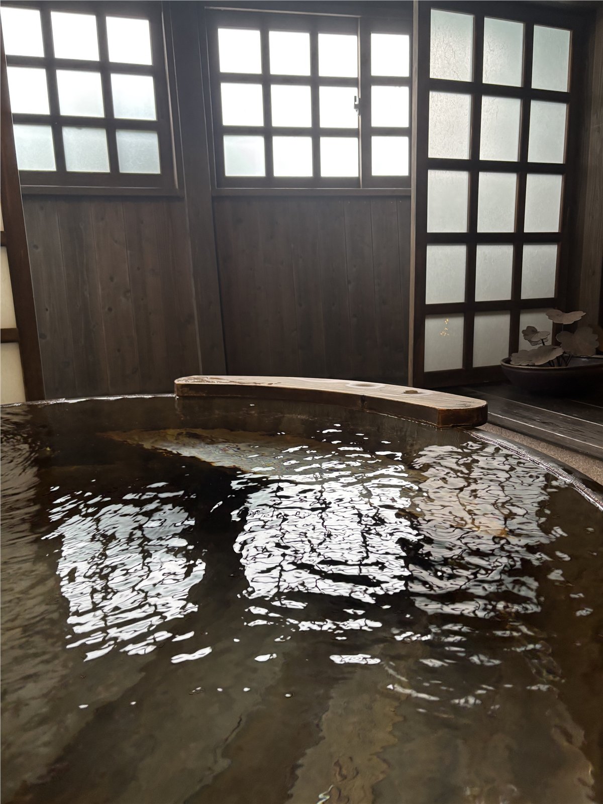 木の格子窓に囲まれた家族湯「山ぼうし」の丸い木桶風呂